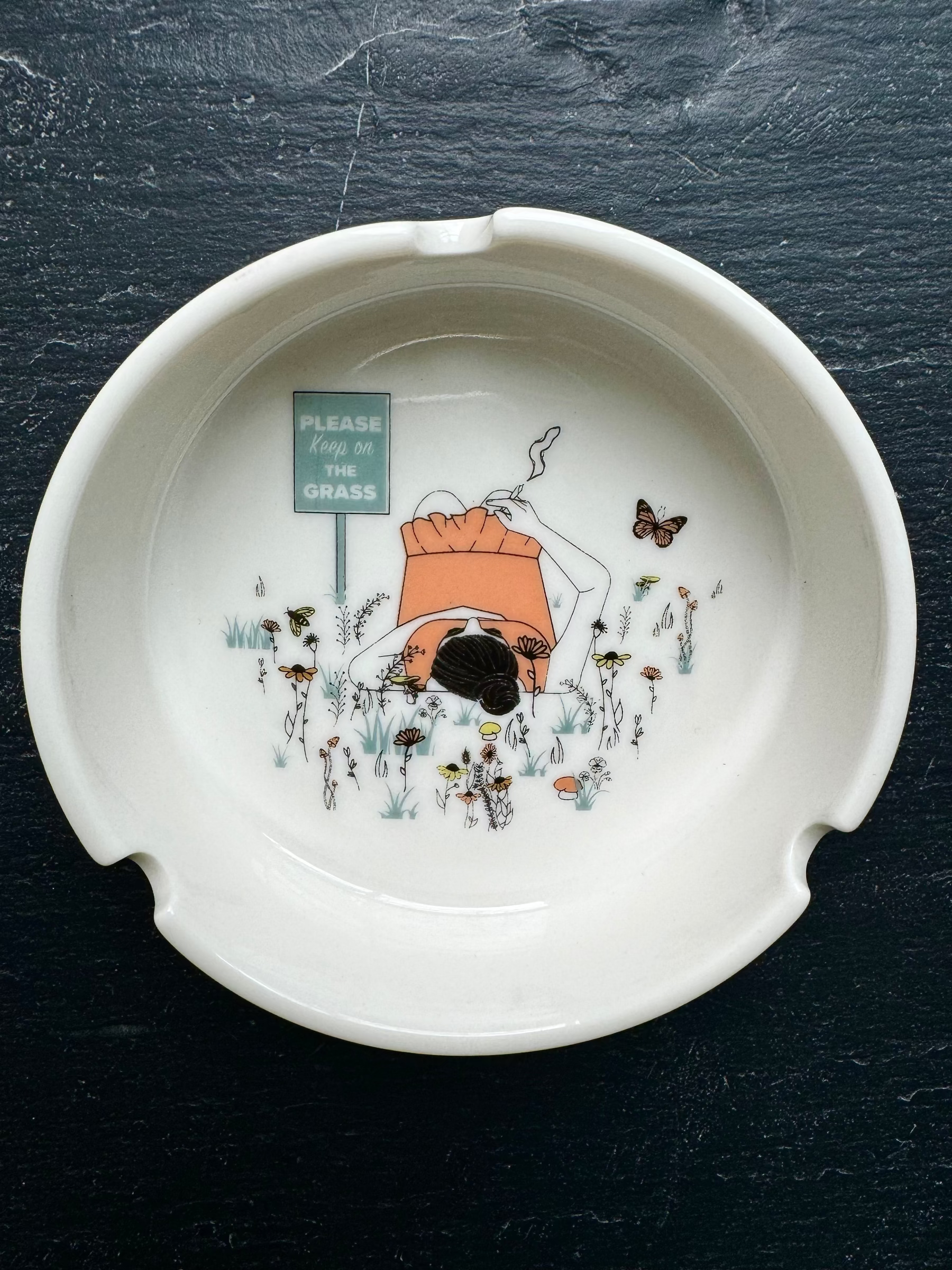 White porcelain ashtray with intricate detail and deep basin; designed to hold ash securely while adding a touch of humor and style to your coffee table decor.