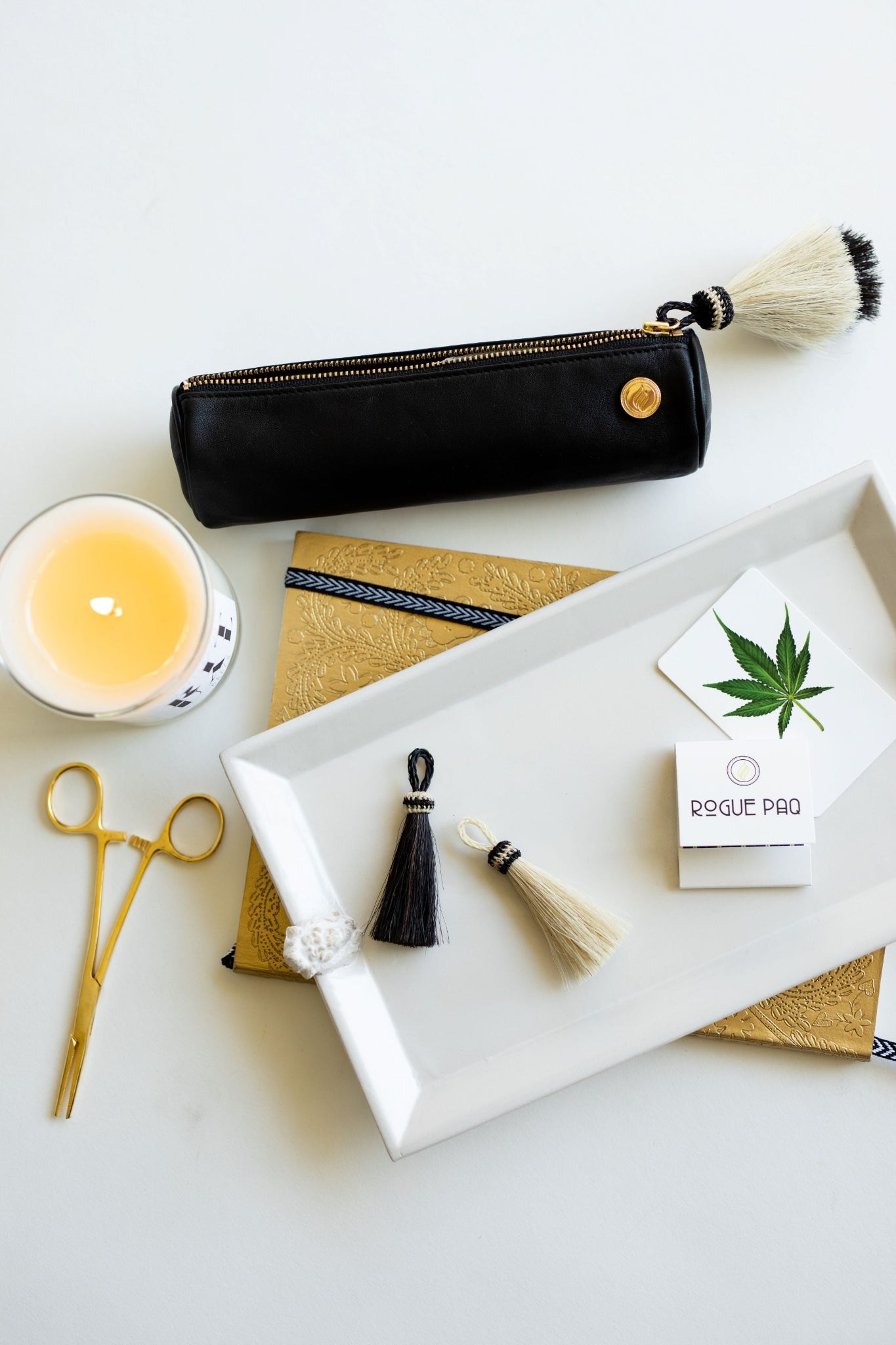 Solo Paq with Hemostat Joint Clip on a clean white background along with other Rogue Paq luxury tools for a high end luxury cannabis smoke session.