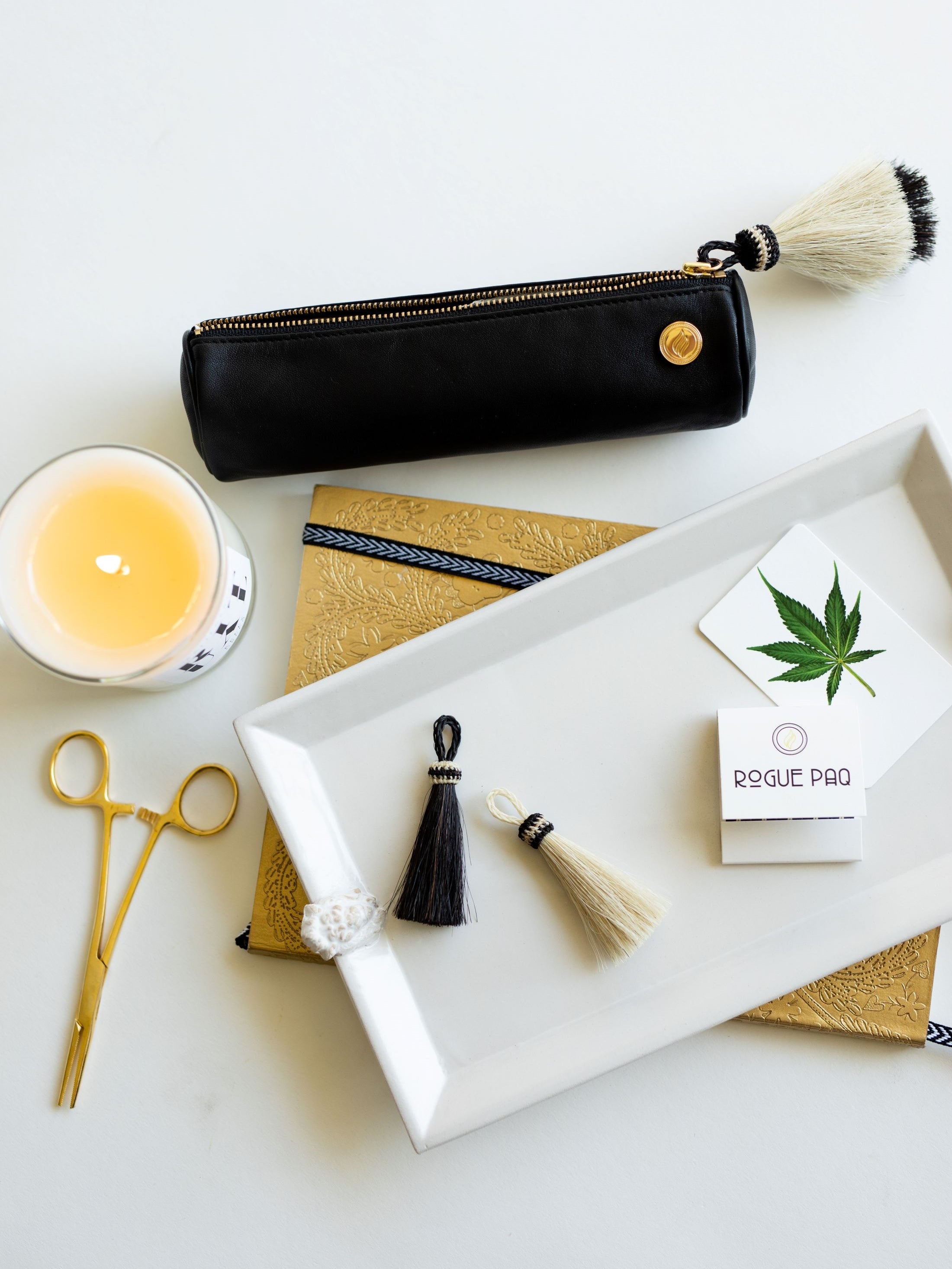 A luxury collaboration between Rogue Paq and KellyGreen: a special edition Solo Paq ritual case in premium black lambskin. The case features a signature handmade horsehair tassel in neutral tones attached to a gold-toned zipper, reflecting a chic and discreet design for cannabis storage.