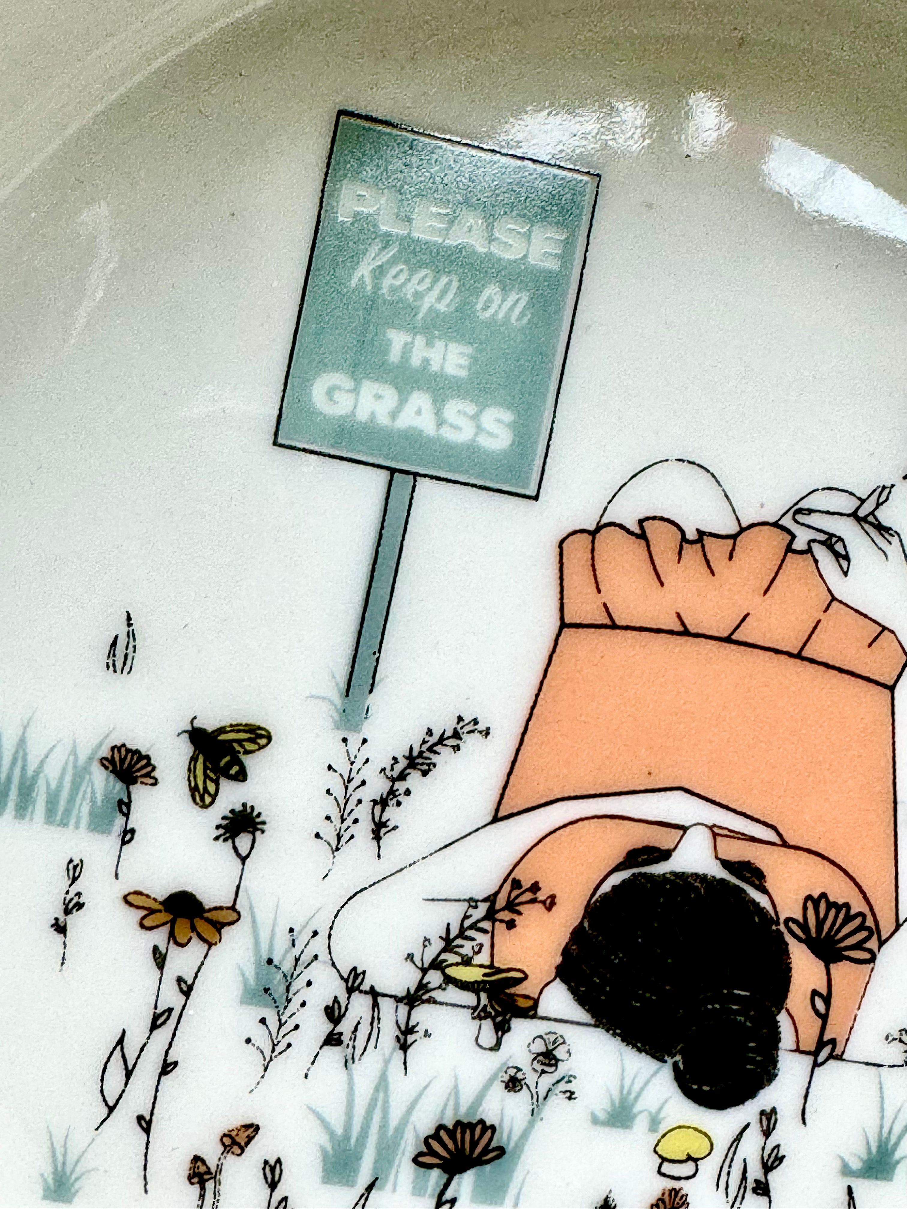 Close up of the sign with the whimsical phrase 'Please Keep On The Grass' for a playful and elegant home accessory for the cannabis enthusiast