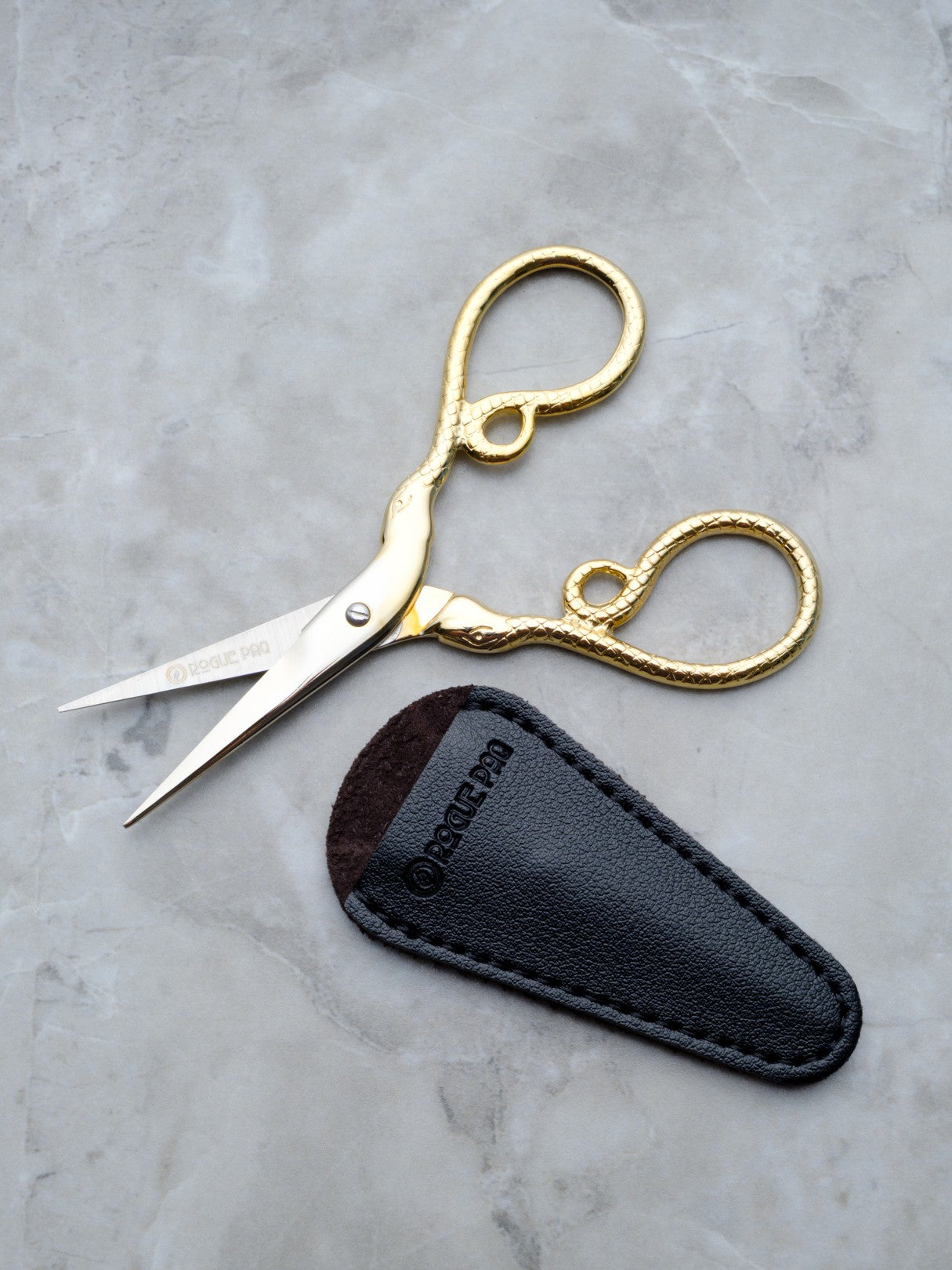 Rogue Paq gold cannabis trimming scissors with a python snake motif for a refined smoking ritual.