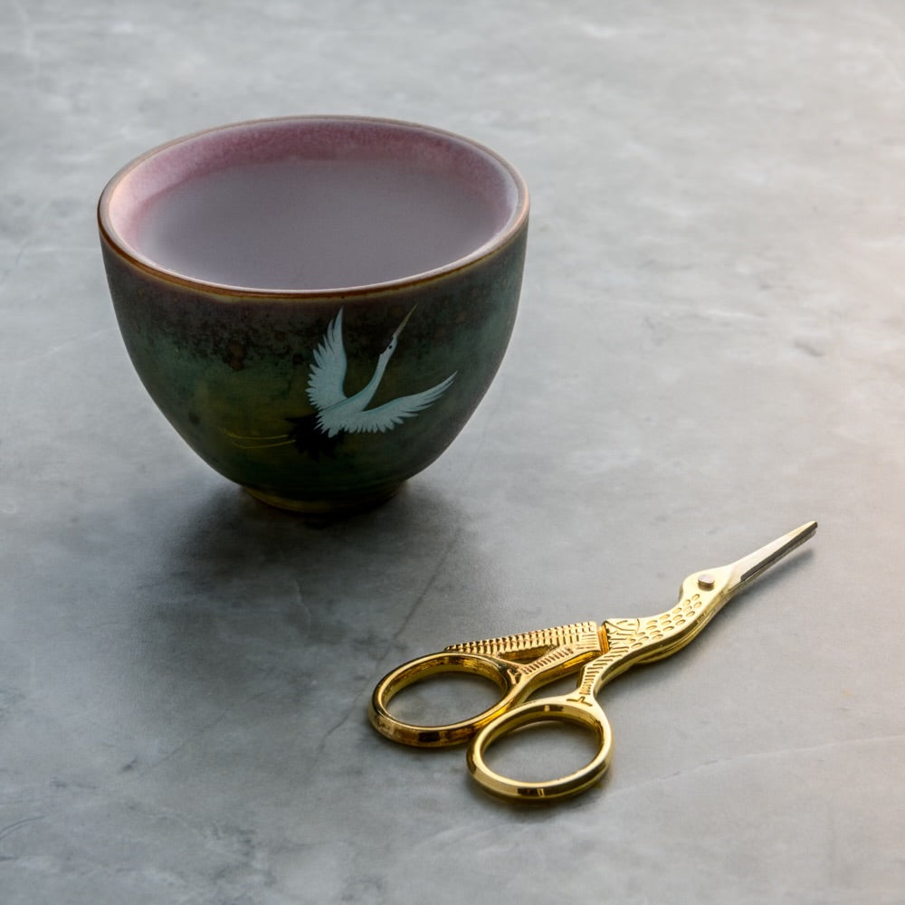 Rogue Paq Crane Manual-Grind Bud Snipping Set featuring gold-tone crane scissors and a stoneware ceramic cup; an elegant alternative to traditional grinders for a mindful cannabis ritual.