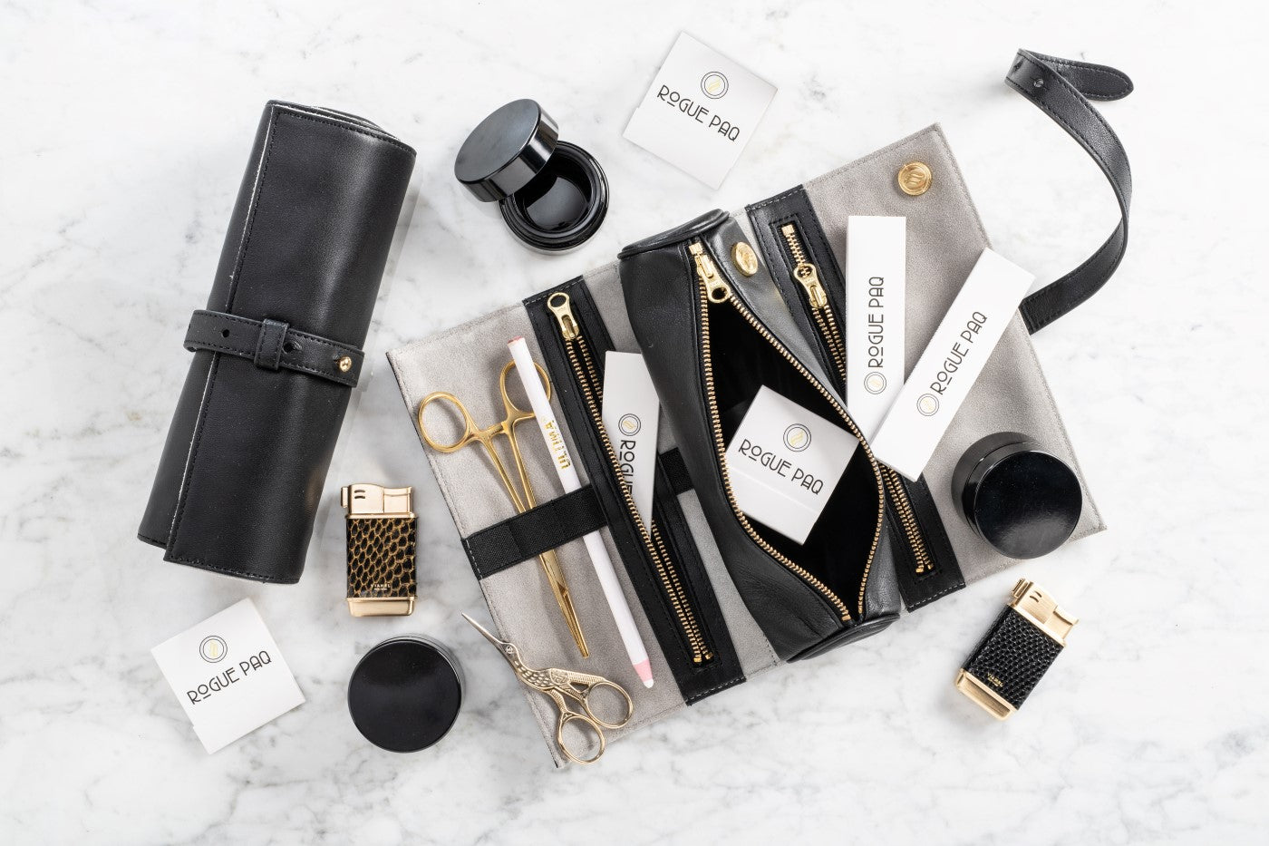 Open Rogue Paq Ritual Case displaying organized interior pockets filled with gold hemostats, crane scissors, and glass jars; a comprehensive kit designed for the organized cannabis ritualist.