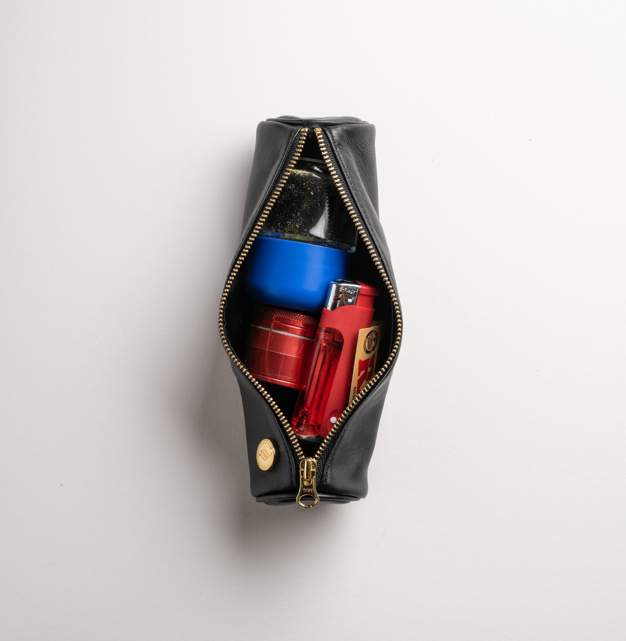 An open view of the Solo Paq ritual case, demonstrating its interior capacity. The scent-suppressant pouch is stuffed with ritual items, showing how it comfortably holds glass jars, grinders, and papers while maintaining shock absorption.