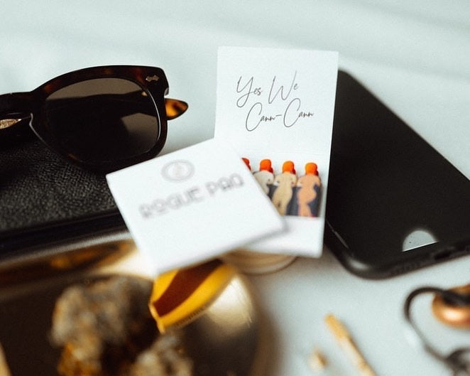 Open book of Yes We Cann Cann matchbooks along with other personal accessories.
